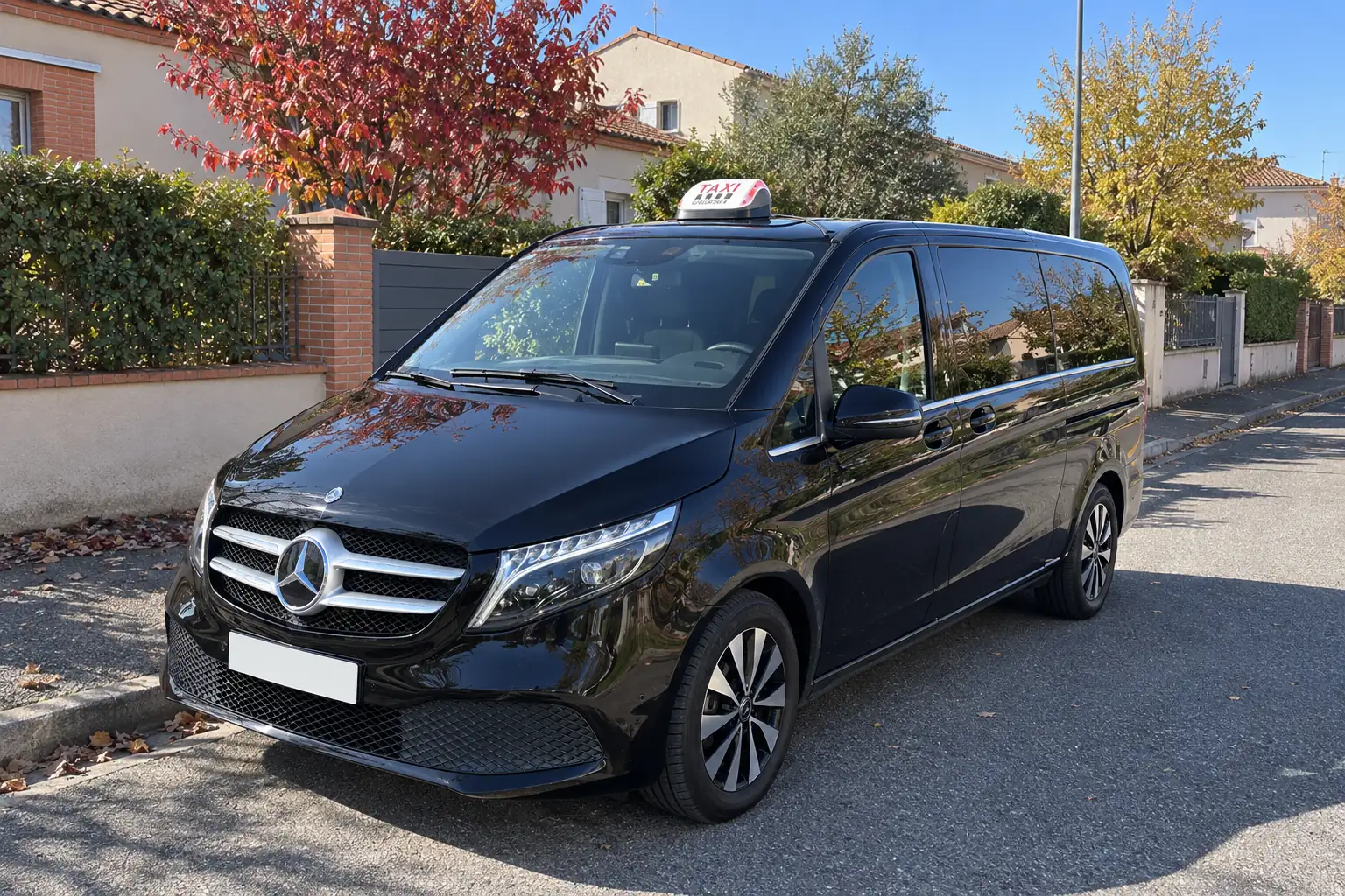 La Classe V de VK Taxi dans une rue résidentielle de l’est toulousain, maisons de brique et arbres d’automne