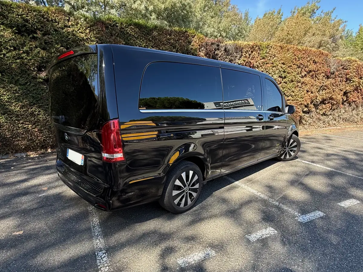 La Mercedes Classe V noire de VK Taxi et Services vue de trois quarts arrière, version longue, garée sur un parking au soleil