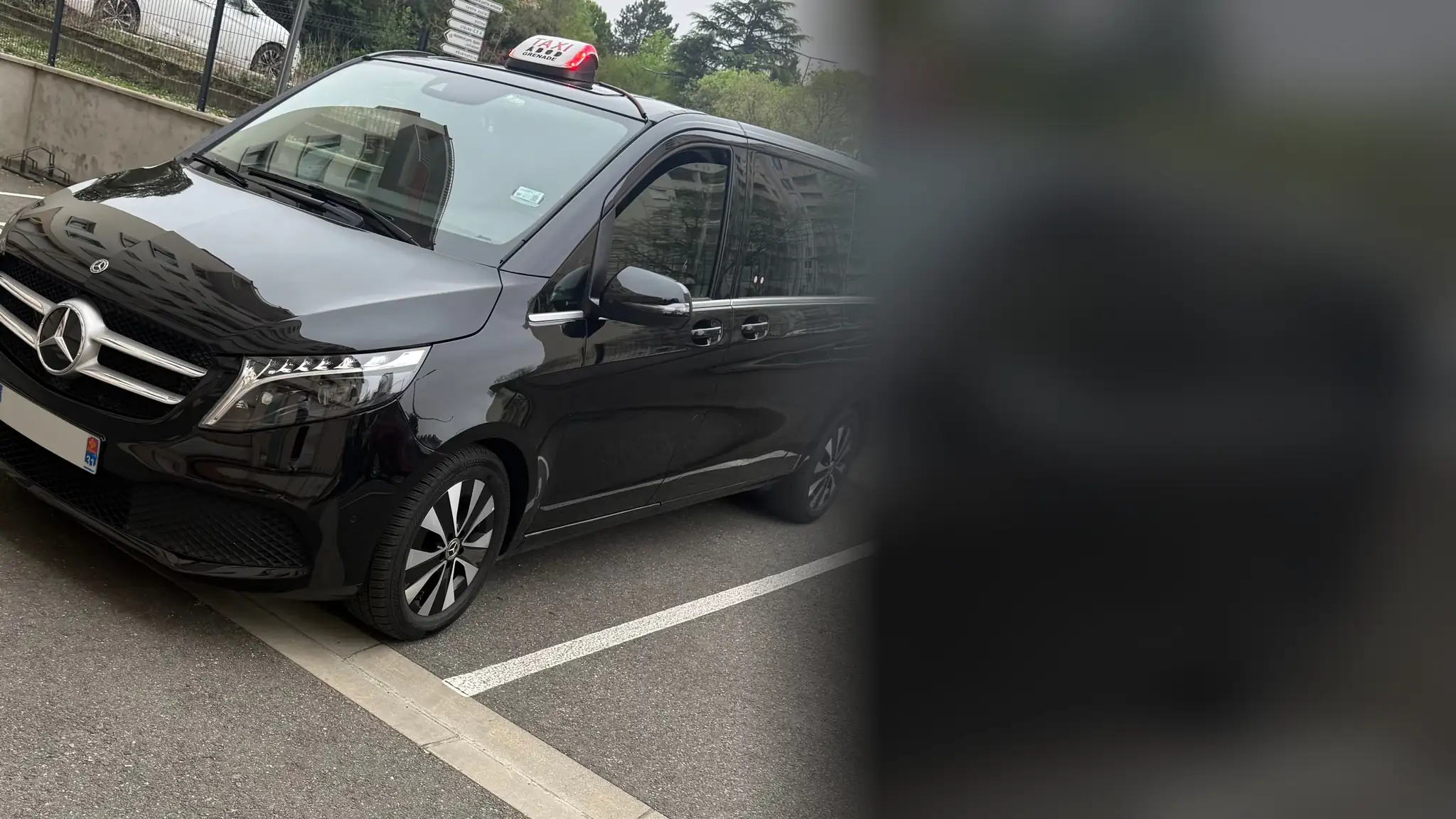 Le Classe V noir de VK Taxi et Services de trois quarts avant, garé sur une place de parking