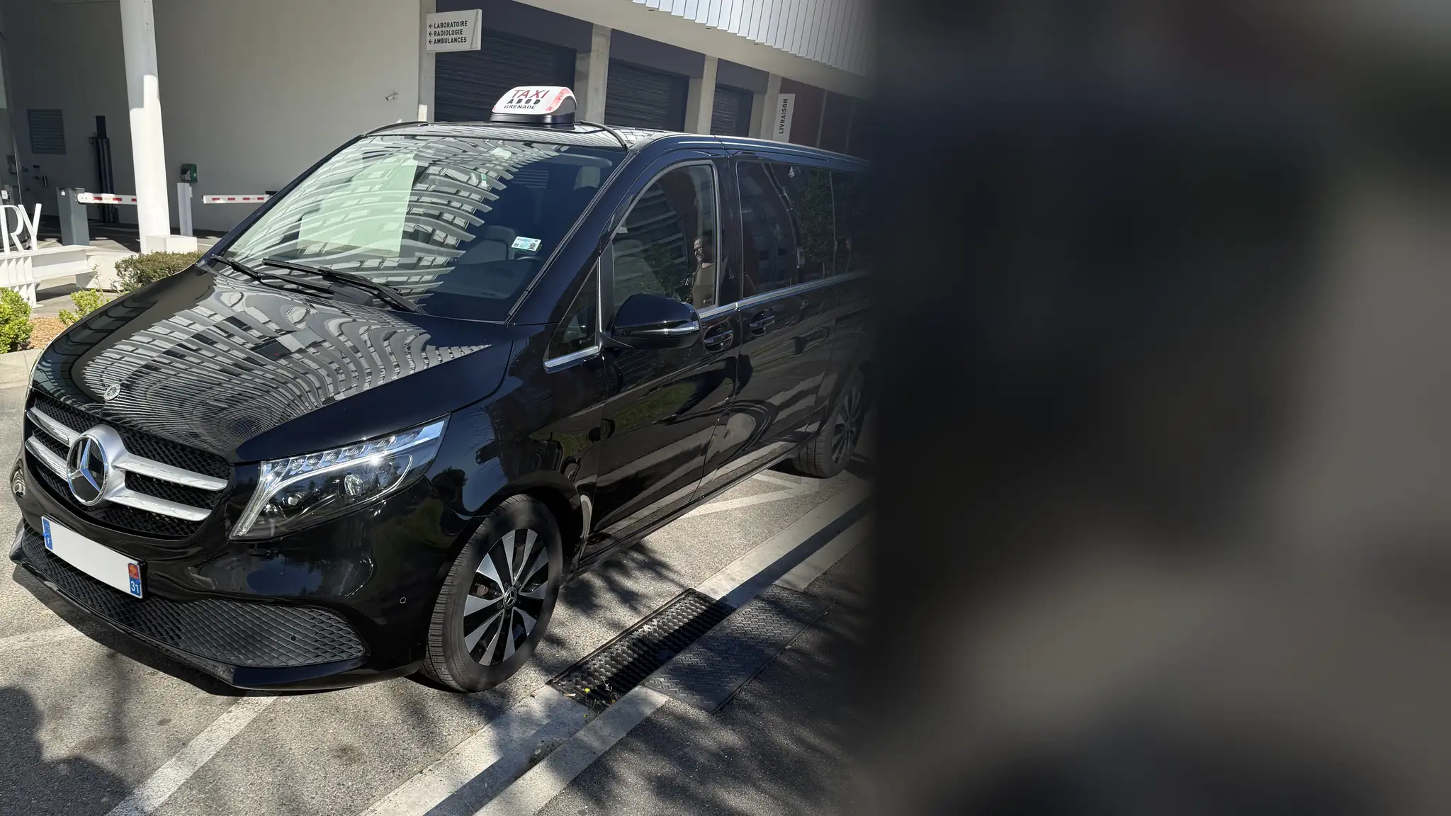 Le Classe V noir de VK Taxi et Services, lumineux TAXI sur le toit, garé devant l’entrée d’un bâtiment, de trois quarts avant