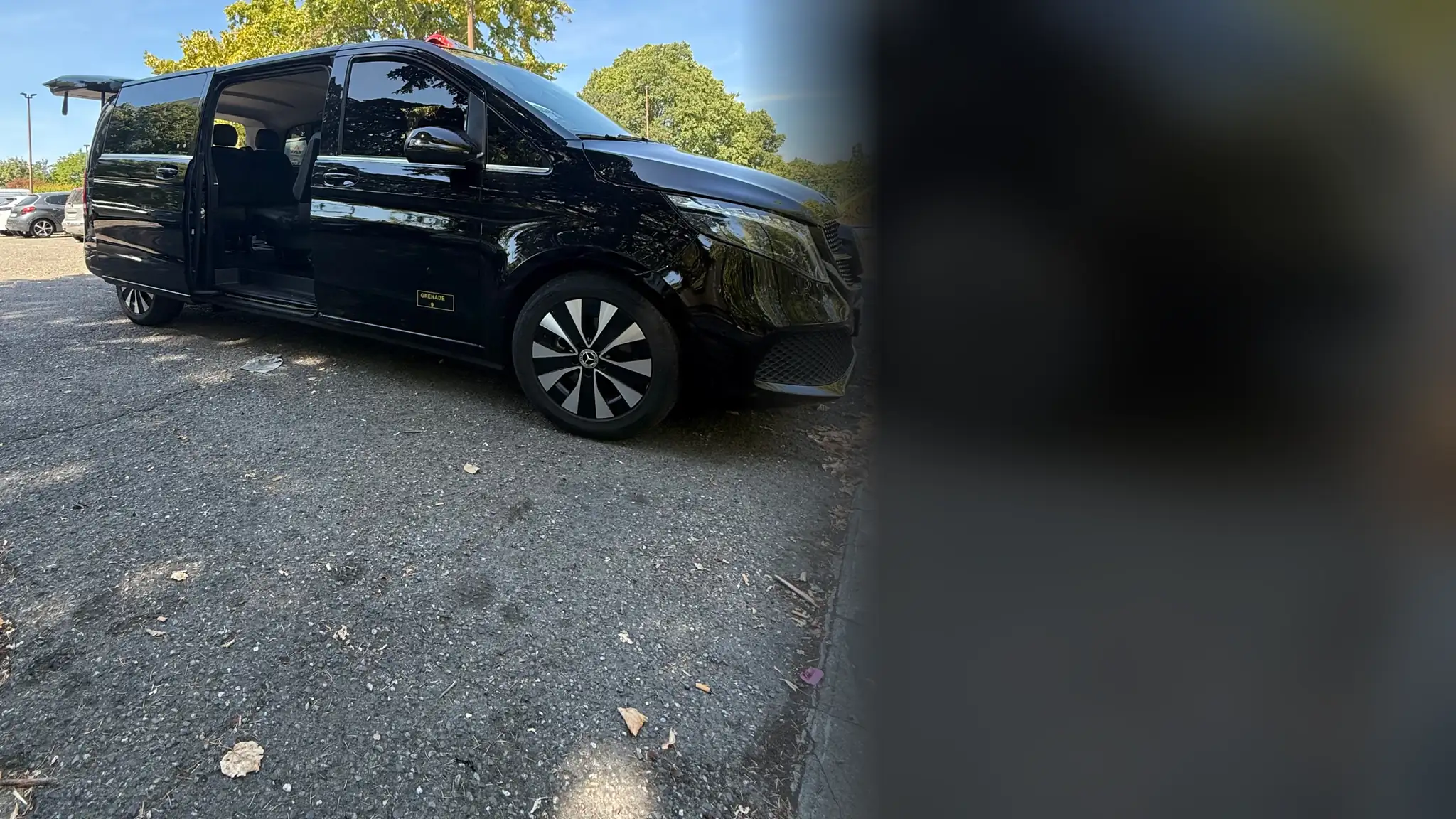 Le Classe V de VK Taxi et Services, porte coulissante ouverte pour faire monter un passager, sous un grand arbre