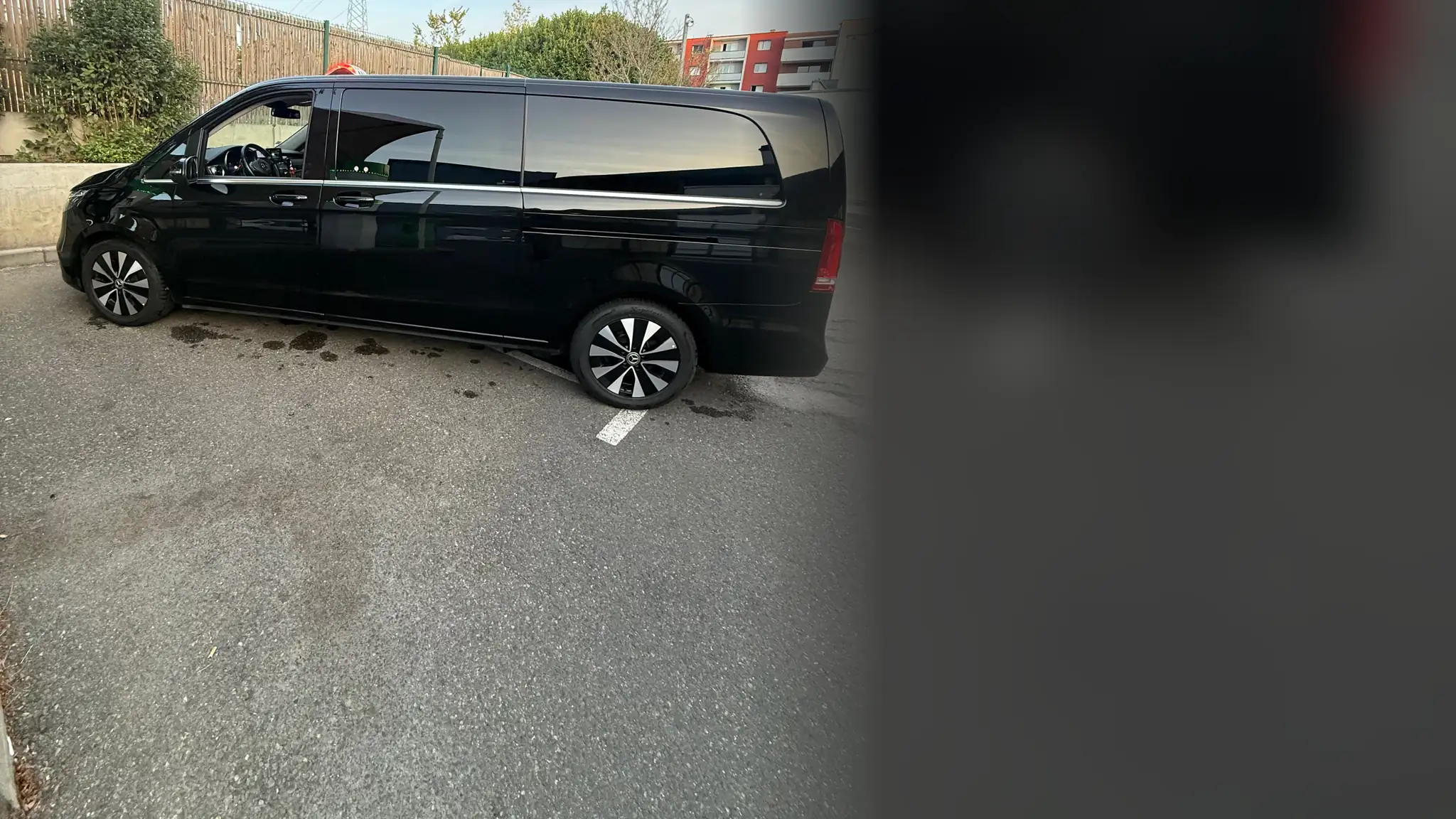 Le Classe V noir de VK Taxi et Services vu de profil, version longue, sur un parking sous un ciel clair